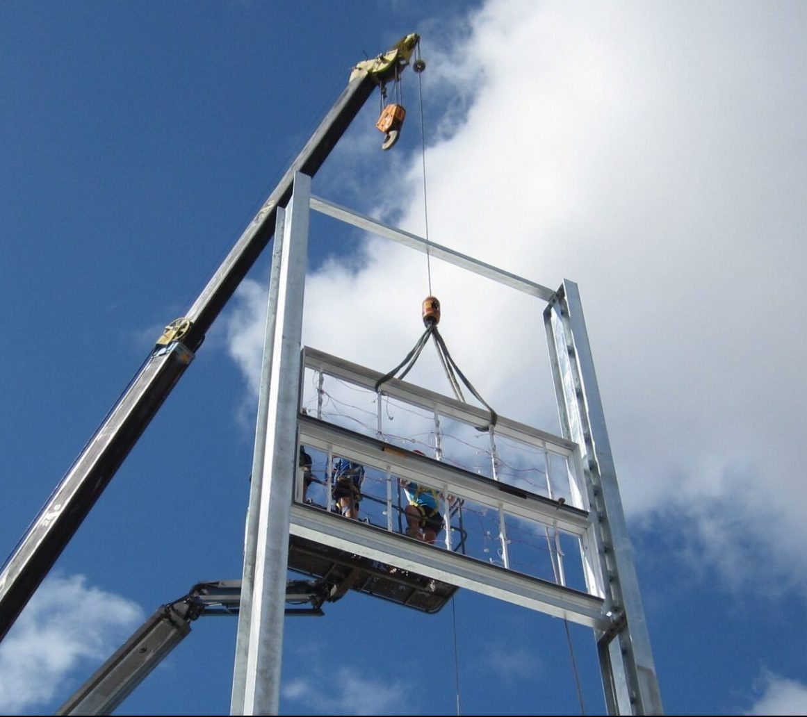Technicians using tools to secure a large digital display sign on a metal frame.